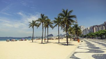 Plams on Copacabana Beach, one of the best places to visit in Brazil, next to the landmark Mosaic on a clear day.