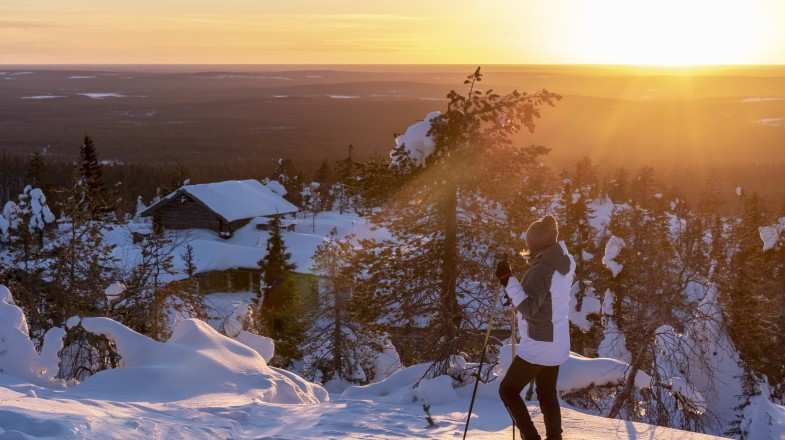 A woman skiing whilst enjoying the view in Finland in winter during sunset.