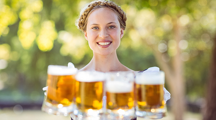 A pretty blonde lady holding beers in the Oktoberfest.