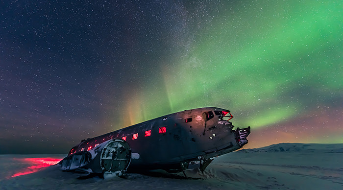 Northern lights over plane wreck on the black beach in Vik